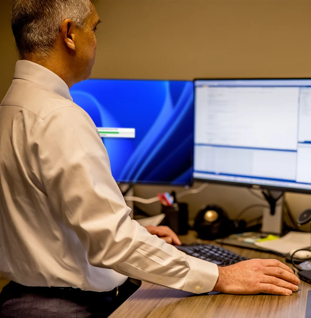 IT services professional working at a standing desk with 2 monitors