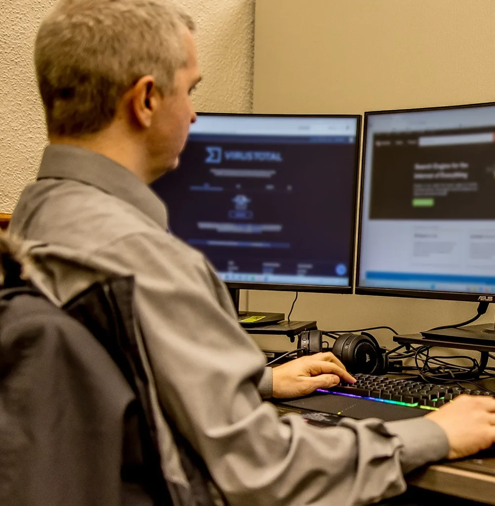 Man sitting at his desk with multiple monitors viewing charts and code