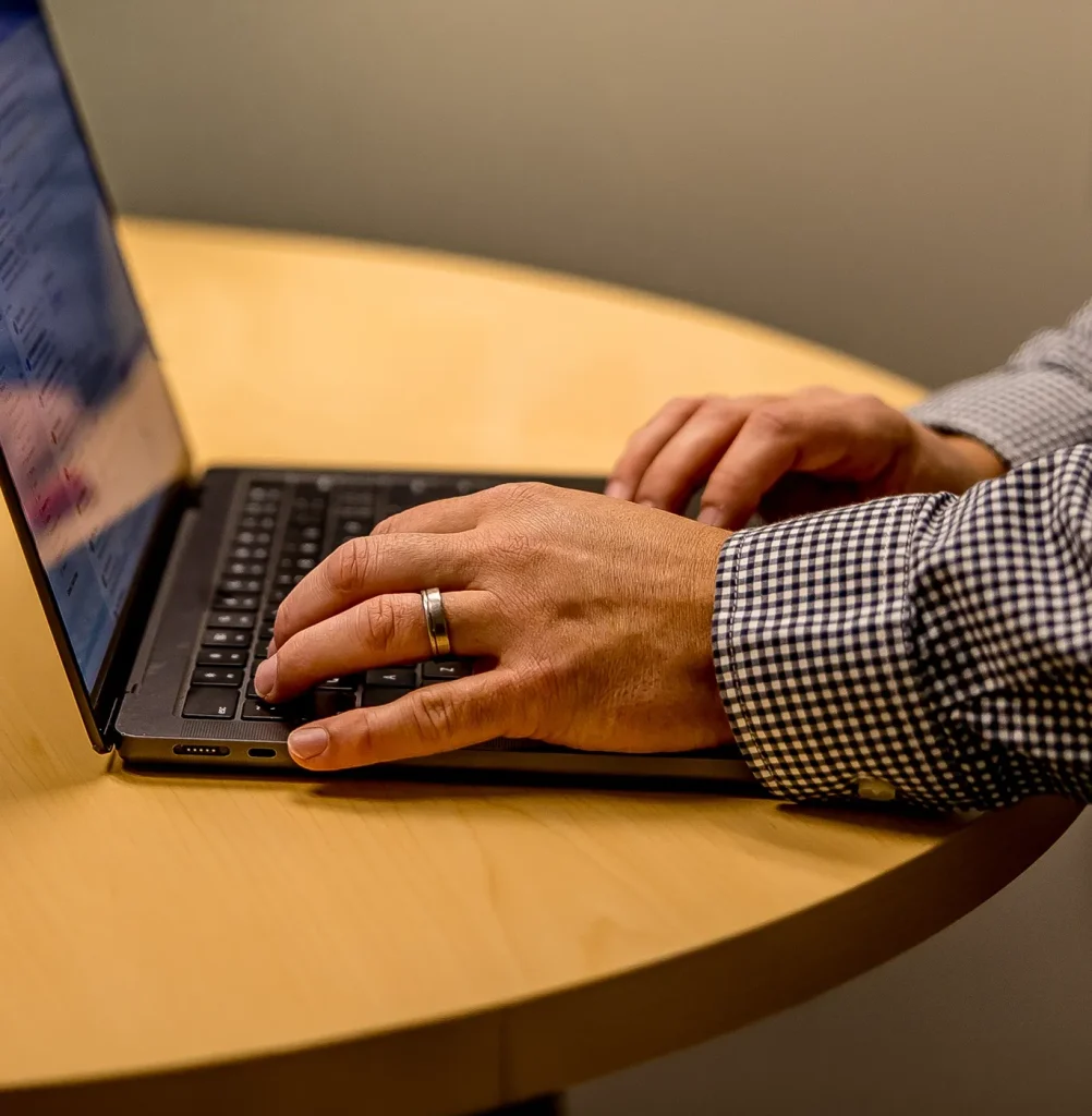 Man sitting at a table on his laptop purchasing equipment